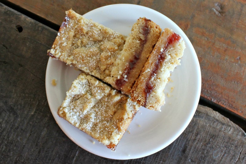 strawberry shortbread bars displayed on a white plate on a wood surface