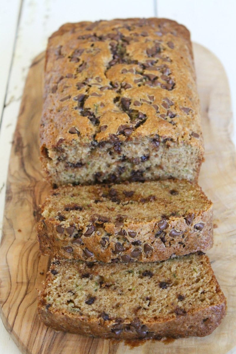 loaf of chocolate chip zucchini bread on a wooden cutting board cut into slices