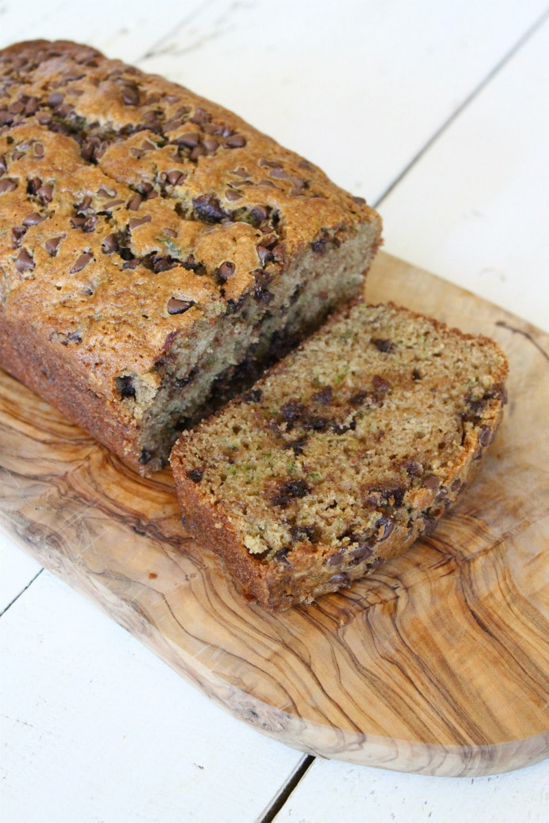 loaf of chocolate chip zucchini bread on a cutting board and slice cut off