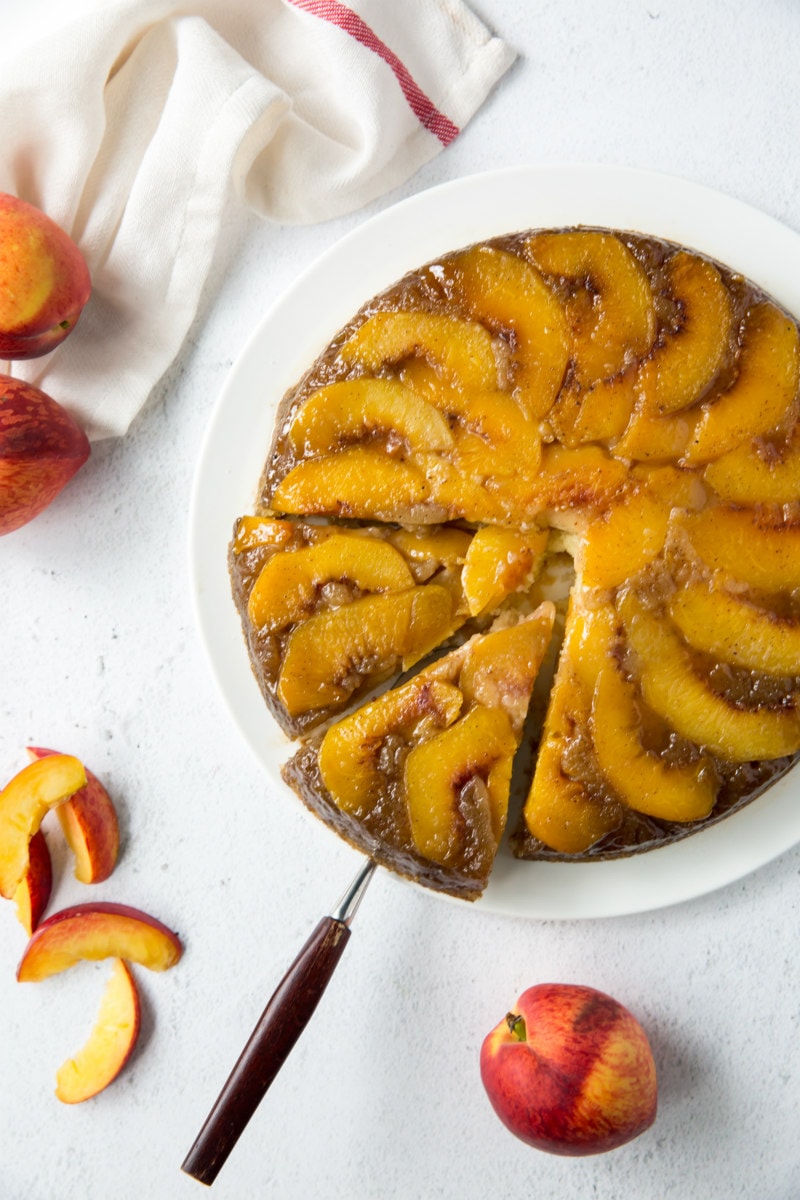 overhead shot of peach upside down cake with a slice being taken out of it