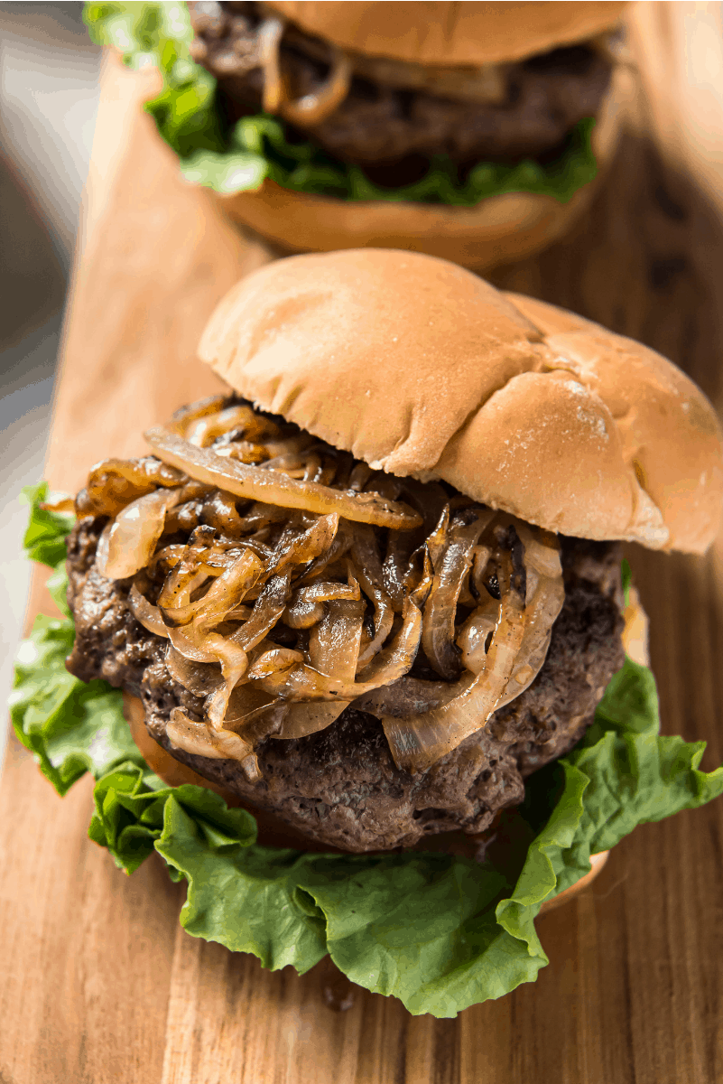 jucy lucy burger with lettuce and tomato and grilled onions piled high