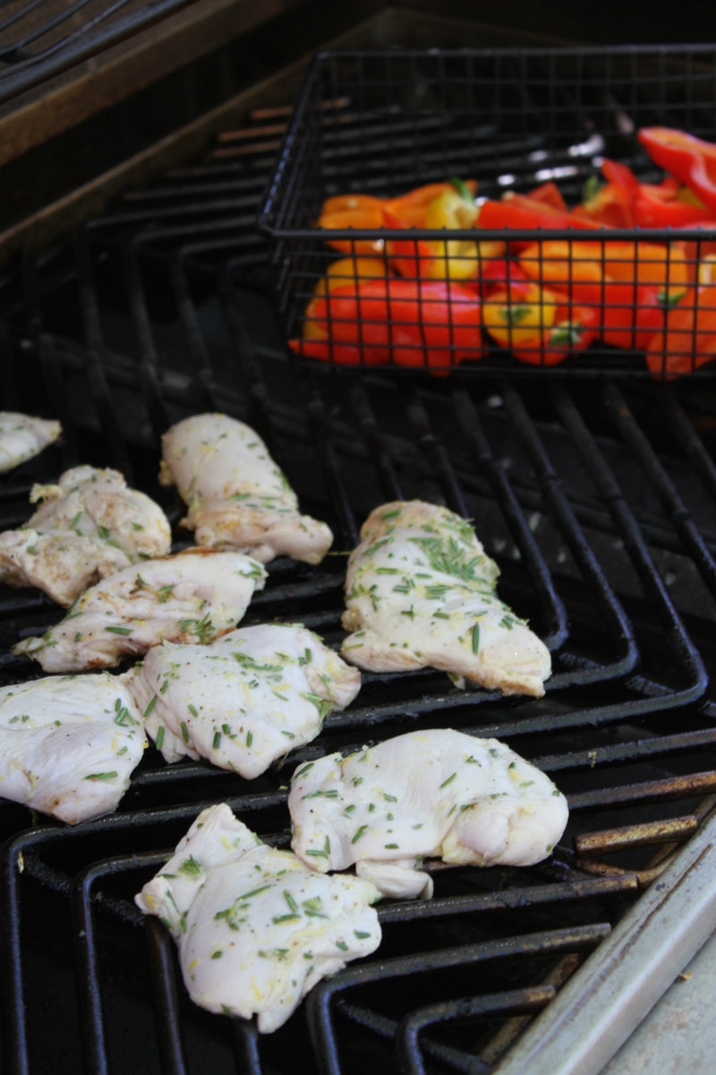 lemon rosemary grilled chicken thighs on the grill with peppers in a grill basket