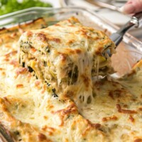 Pulling out a cheesy slice of vegetable lasagna out of the lasagna pan