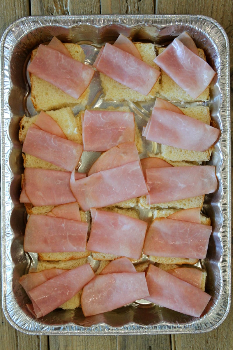 overhead shot of pan of cuban sliders showing process of placing ham on top of buns