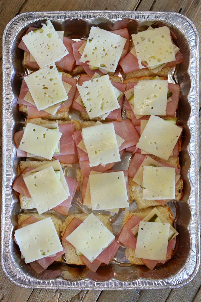 overhead shot of the process of making a pan of cuban sliders with layers of ham and cheese