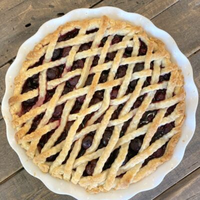 overhead shot of cherry amaretto pie with lattice pie crust on a wooden board