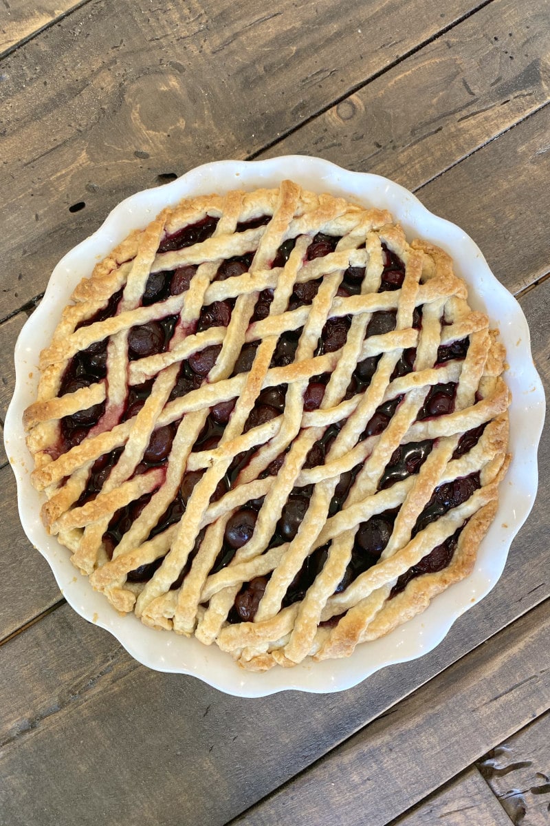 overhead shot of cherry amaretto pie with lattice pie crust on top on a wooden board