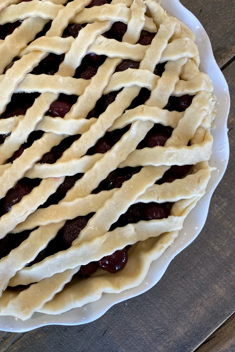overhead shot of lattice pie crust topping cherry pie before baking