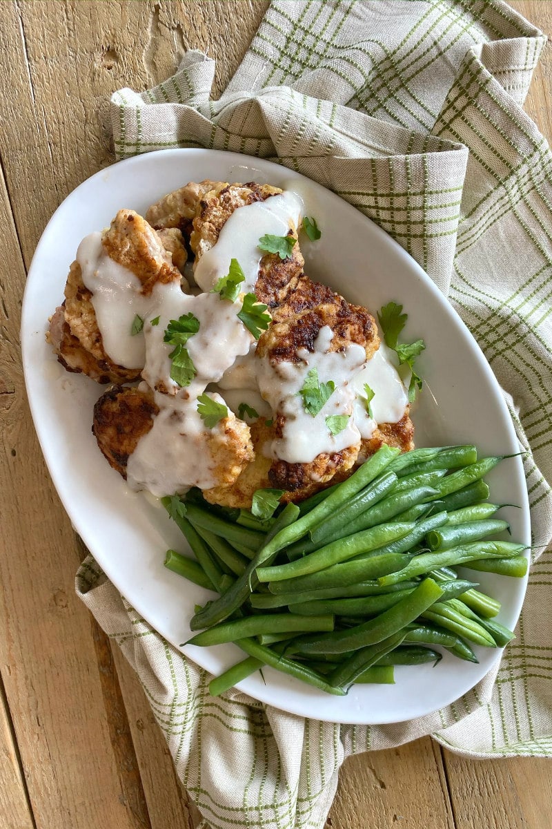 Chicken Fried Pork served with white country gravy and steamed green beans