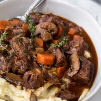 serving of beef bourguignon with potato in a white bowl