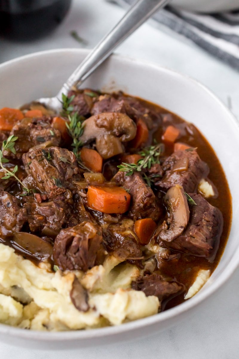 serving of beef bourguignon with potato in a white bowl