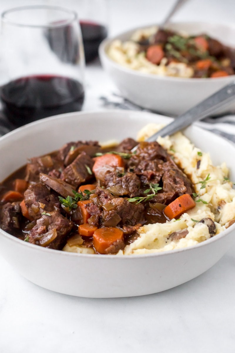 serving of beef bourguignon with mashed potato in a white bowl