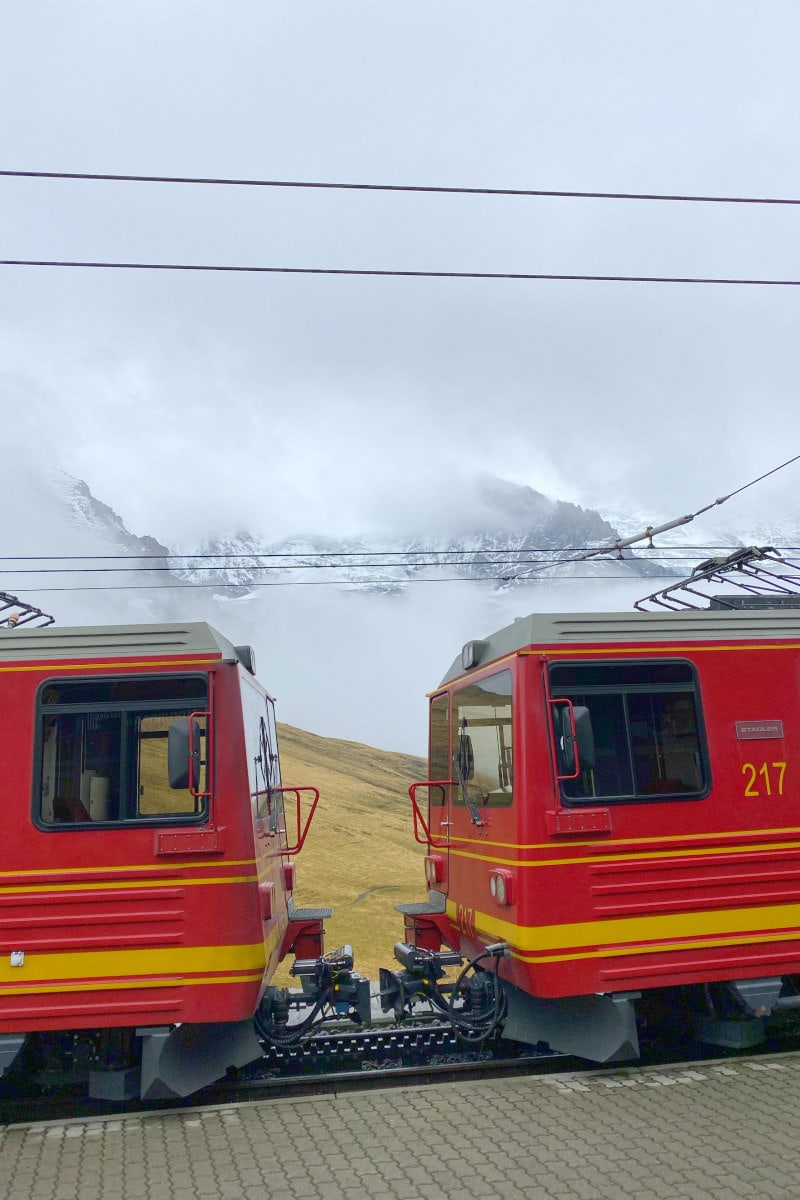 Red train At the top of the mountain under the clouded Swiss Alps