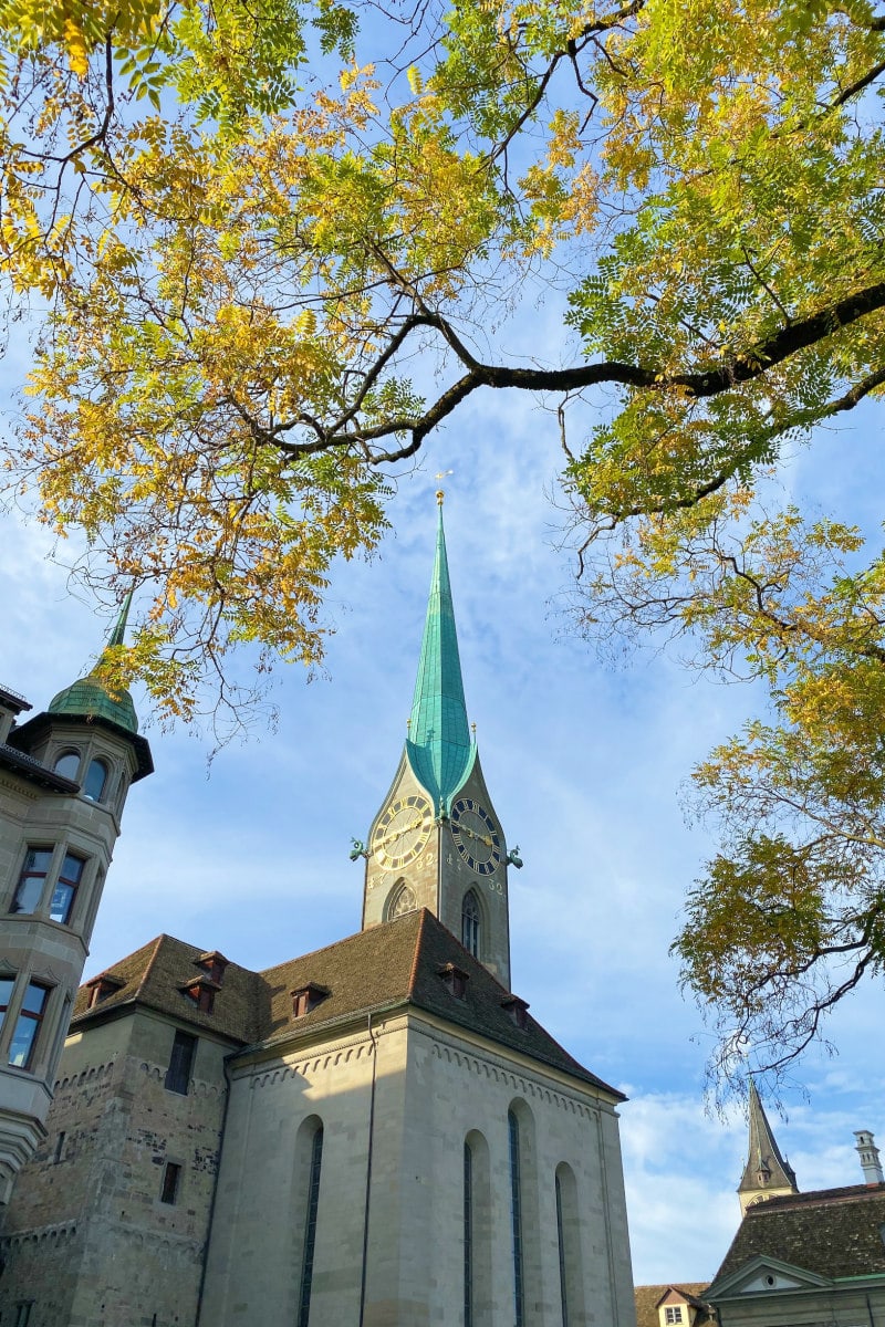 Looking up at a church spier in Zurich through the trees