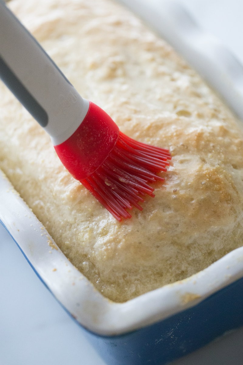 Adding Melted Butter to English Muffin Bread with a red silicone brush