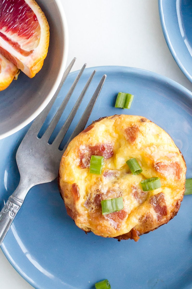 Copycat Starbucks Egg Bites recipe from RecipeGirl.com : Bacon and Gruyere Egg Bites overhead shot of copycat starbucks egg bites displayed with a fork on a blue plate
