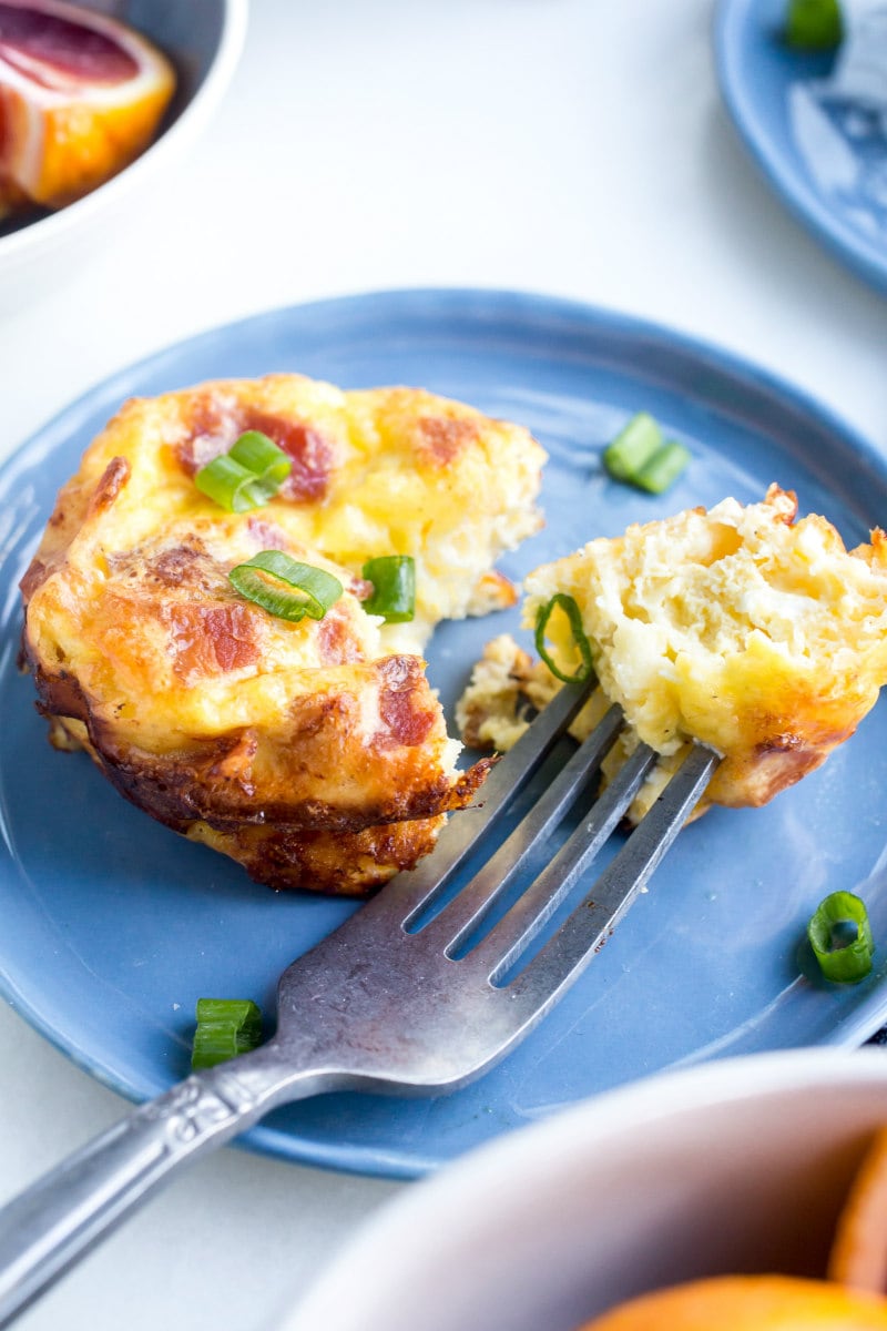 Copycat Starbucks Egg Bites recipe from RecipeGirl.com : Bacon and Gruyere Egg Bites using a fork to eat starbucks copycat egg bites off a blue plate