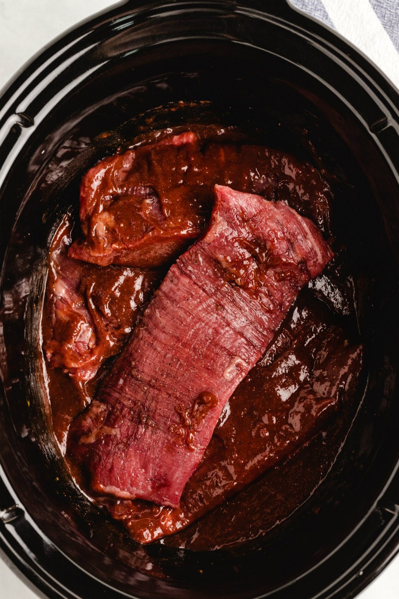 adding steak and sauce to slow cooker
