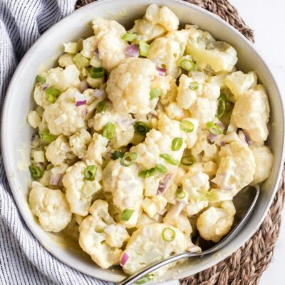 cauliflower potato salad in a white bowl on a striped napkin