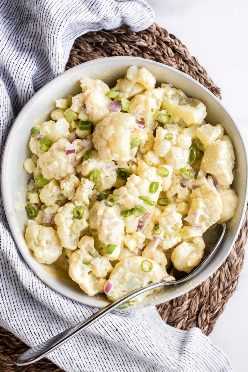 cauliflower potato salad in a white bowl on a striped napkin