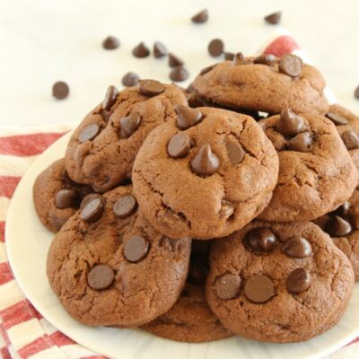Piled Chocolate Chocolate Chip Pudding Cookies on a white plate with a striped napkin