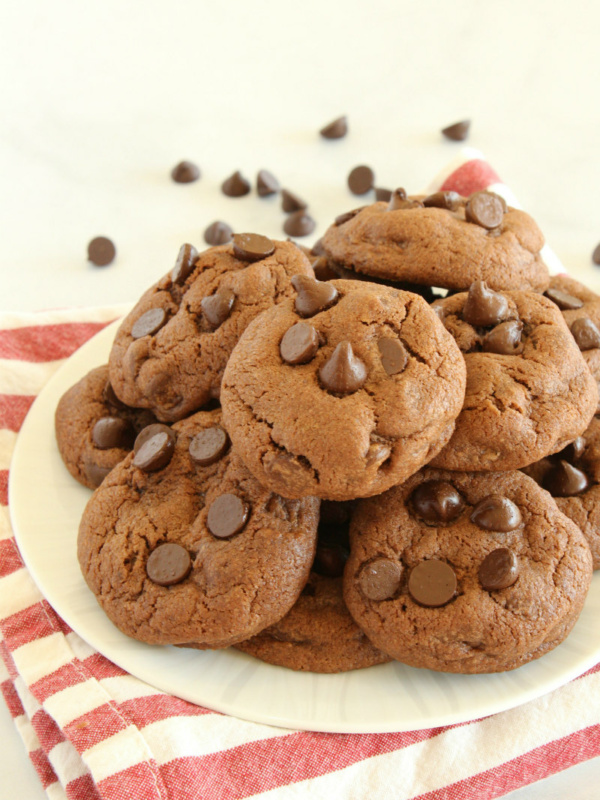 Piled Chocolate Chocolate Chip Pudding Cookies on a white plate with a striped napkin