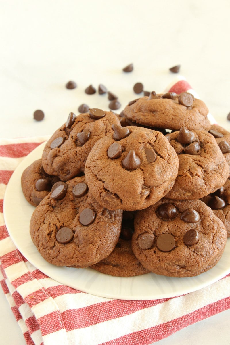 Piled Chocolate Chocolate Chip Pudding Cookies on a white plate with a striped napkin