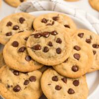 chocolate chip cookies displayed on a white platter on top of a white and gray plaid napkin