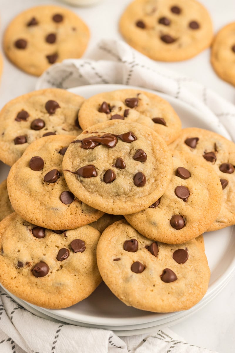 chocolate chip cookies displayed on a white platter on top of a white and gray plaid napkin