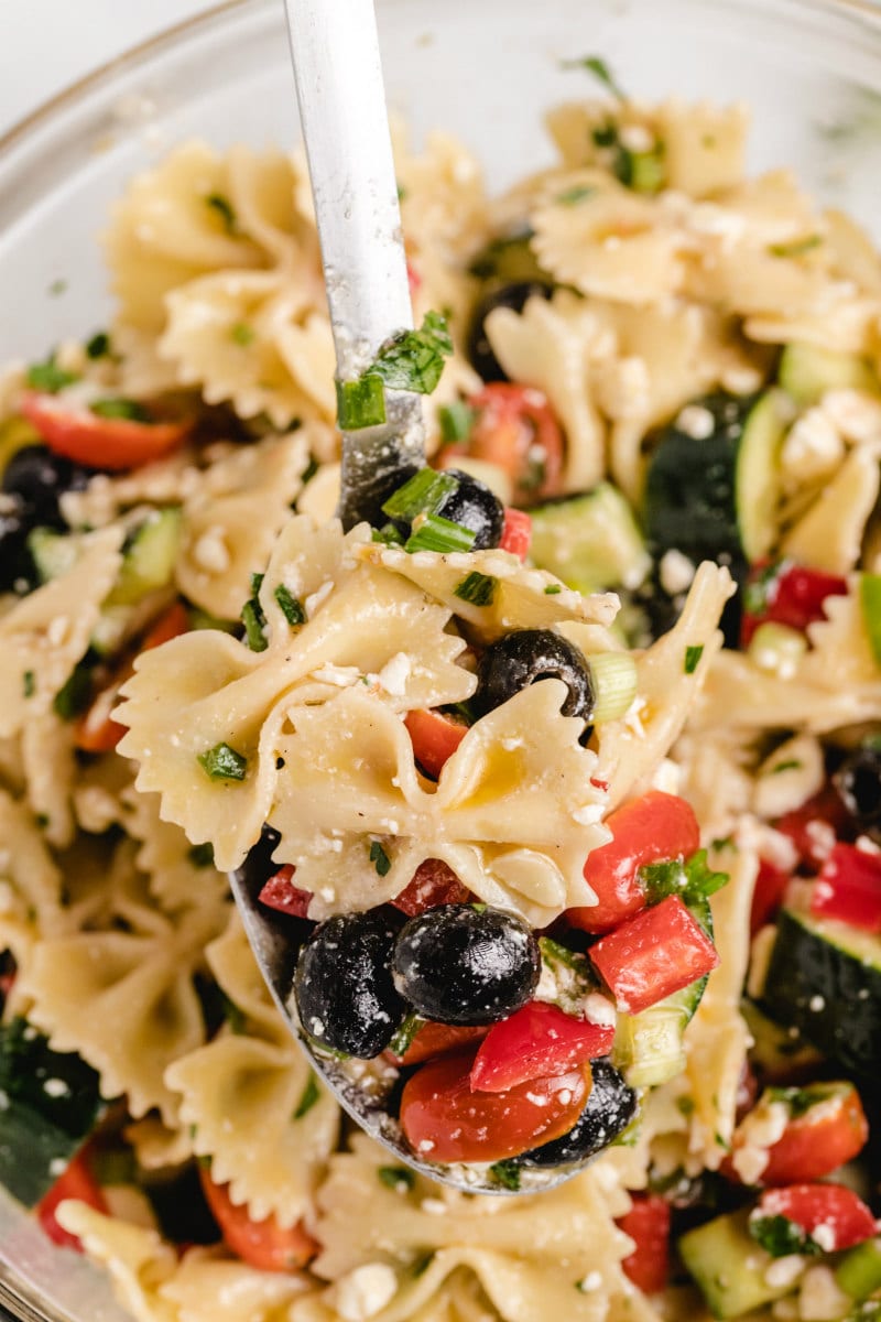 overhead shot of bow tie pasta salad with a spoonful of the salad being lifted out of the bowl