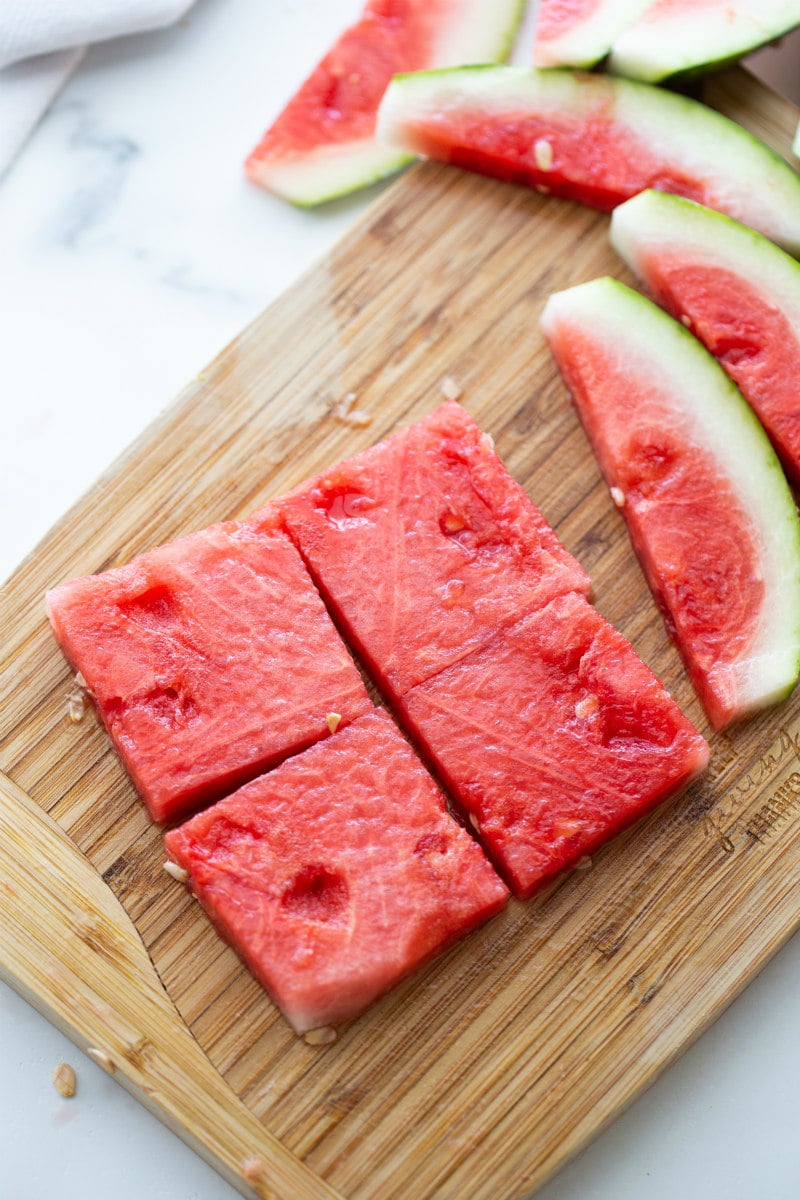 slices of fresh watermelon cut into squares on a cutting board