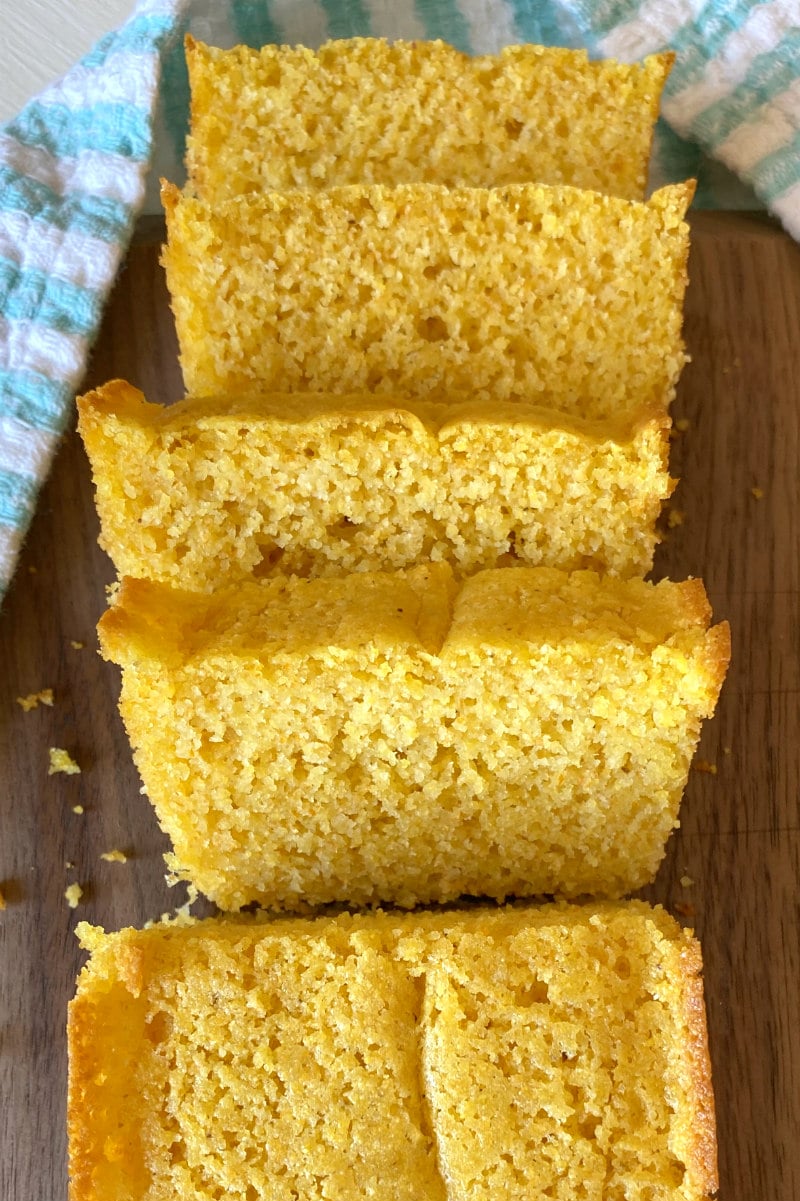 overhead shot of buttermilk cornbread sliced on a cutting board set on a white/teal striped cloth napkin