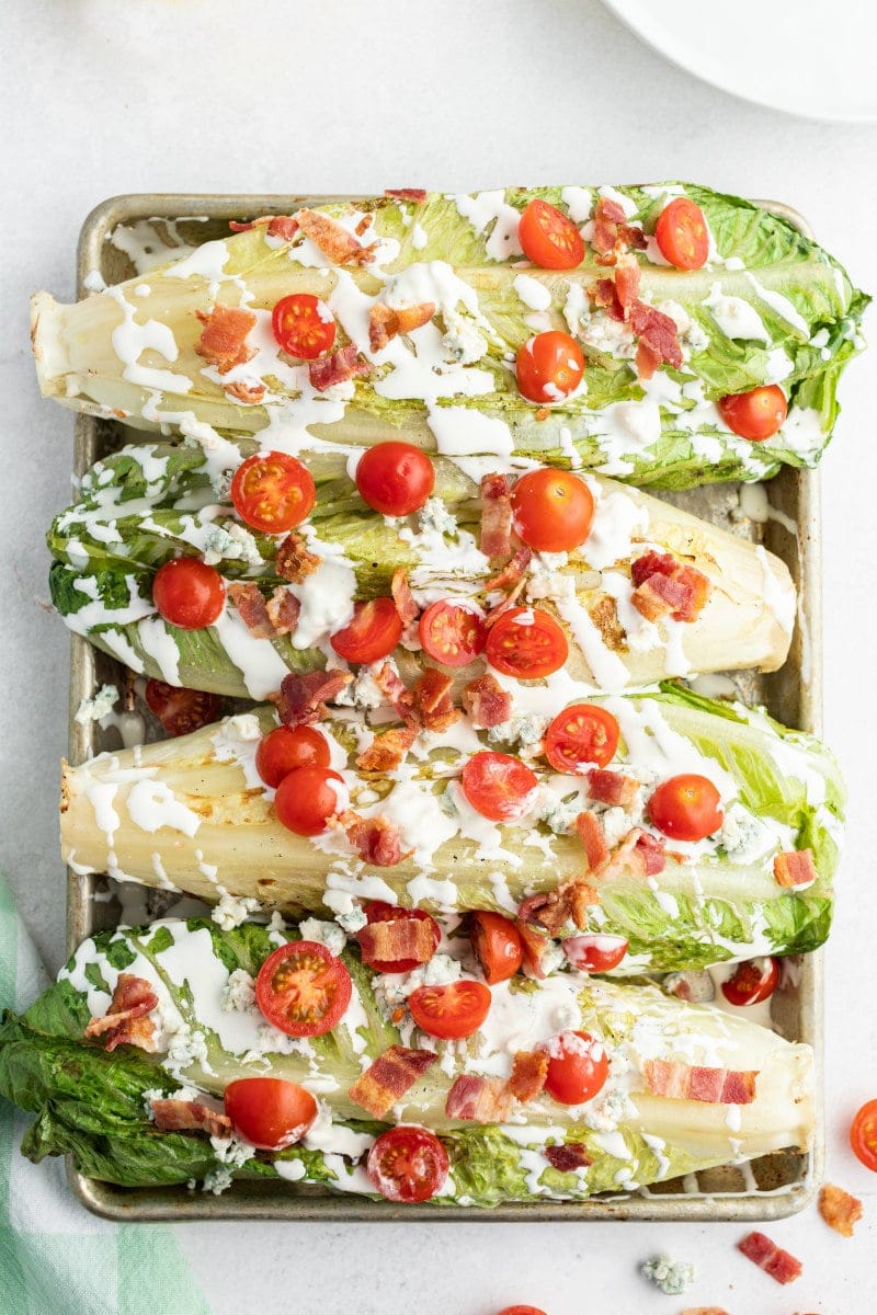 four grilled wedge salads displayed on a baking sheet