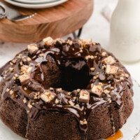 chocolate wasted cake displayed on a white plater with stack of white plates and milk in background