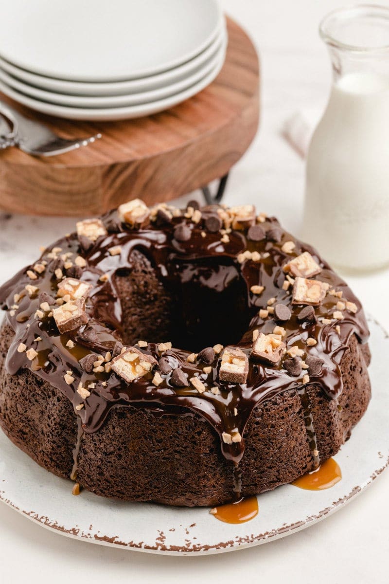 chocolate wasted cake displayed on a white plater with stack of white plates and milk in background