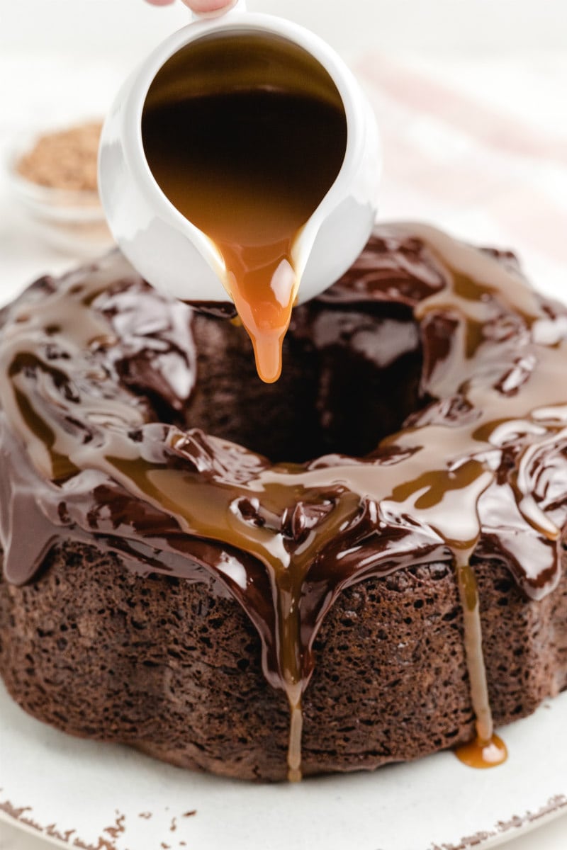 pouring caramel onto chocolate wasted cake from a white pitcher