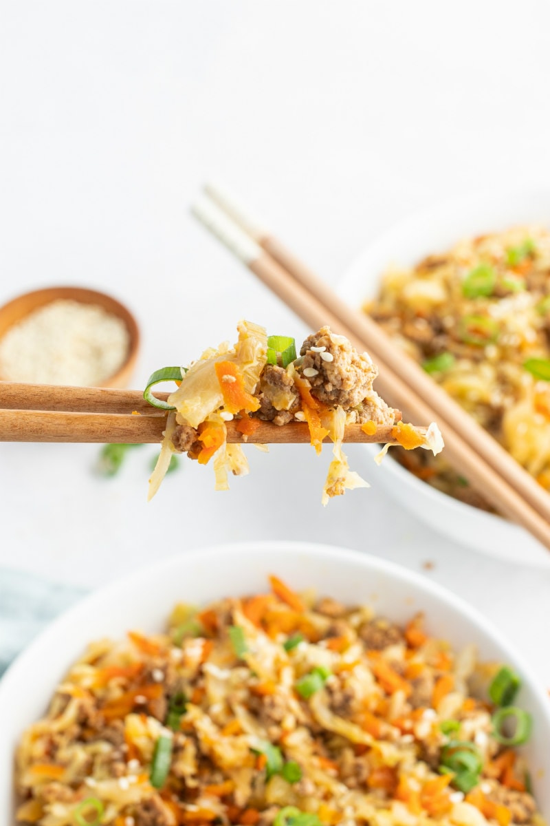 chopsticks with a bite of egg roll in a bowl