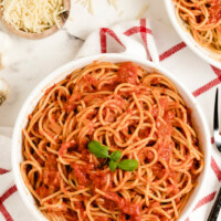 pasta pomodoro in a white bowl garnished with fresh basil