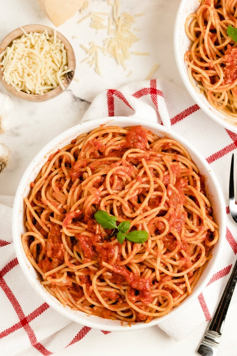 pasta pomodoro in a white bowl garnished with fresh basil