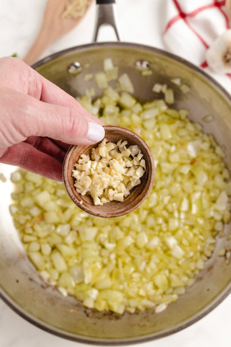 adding garlic to onions in a skillet