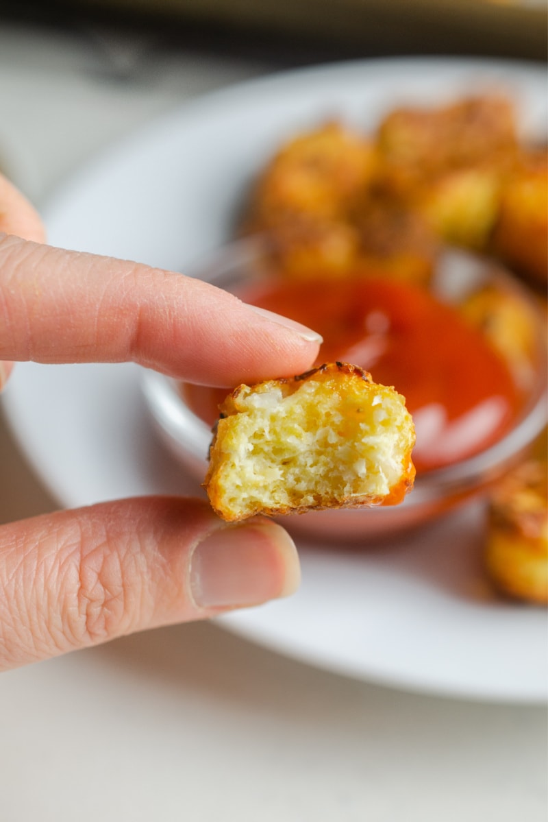 hand holding cauli tot with bite taken out of it