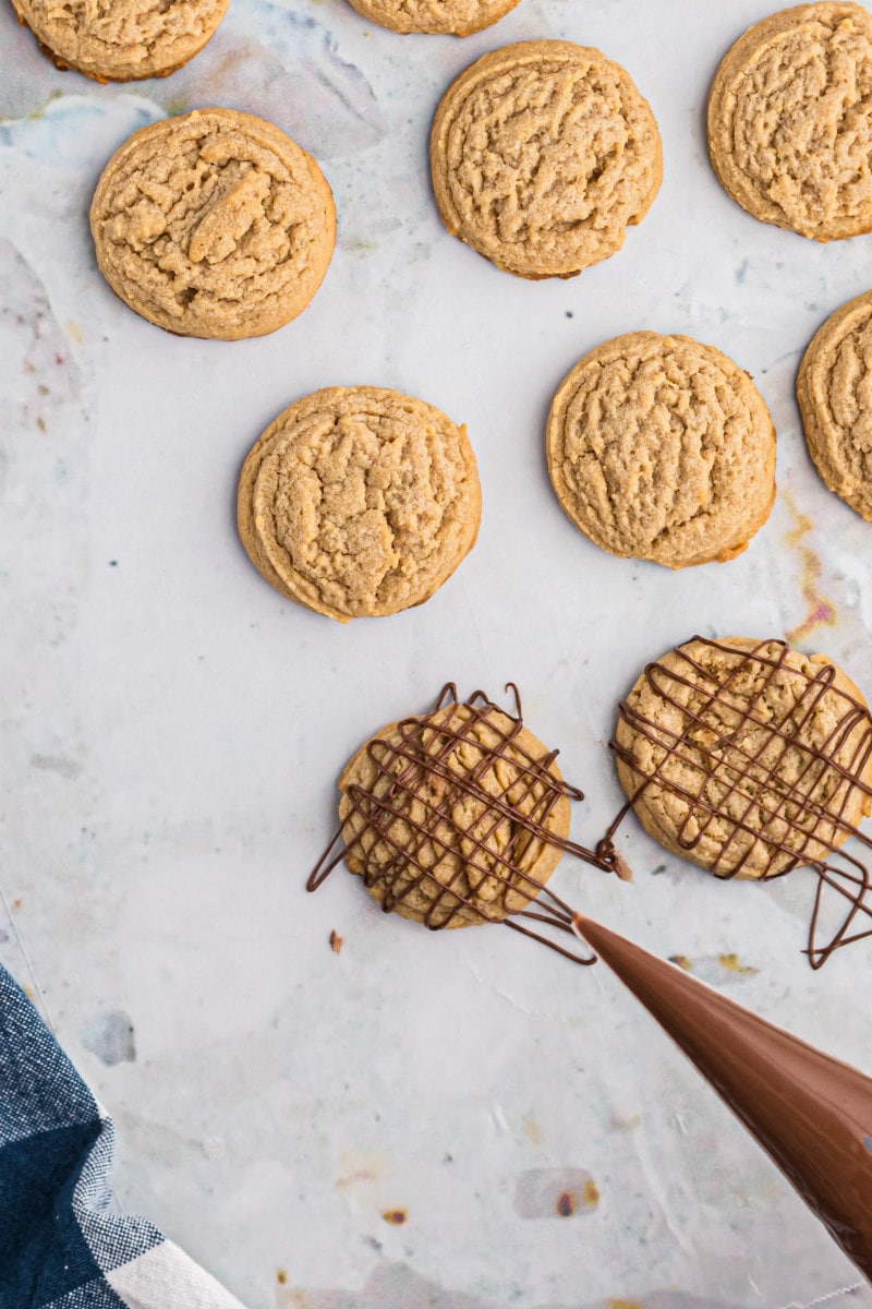 drizzling chocolate onto peanut butter cookies
