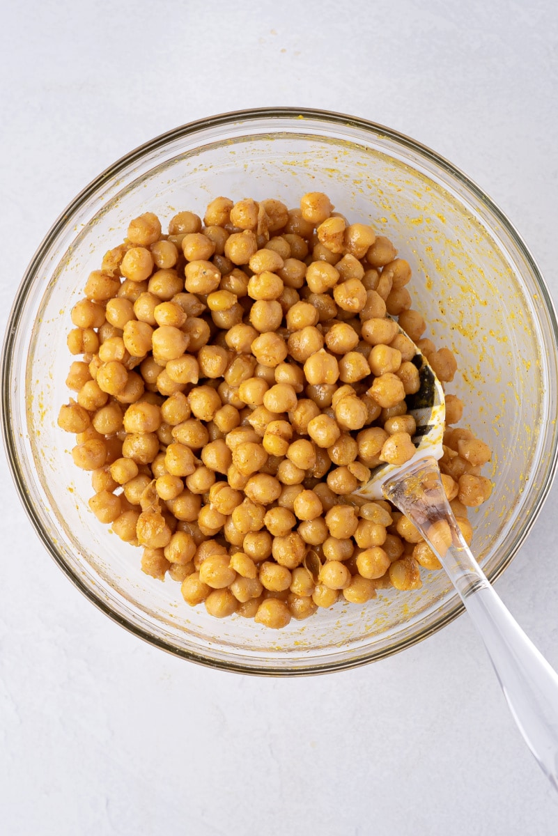 chickpeas in a bowl tossed with olive oil and spices