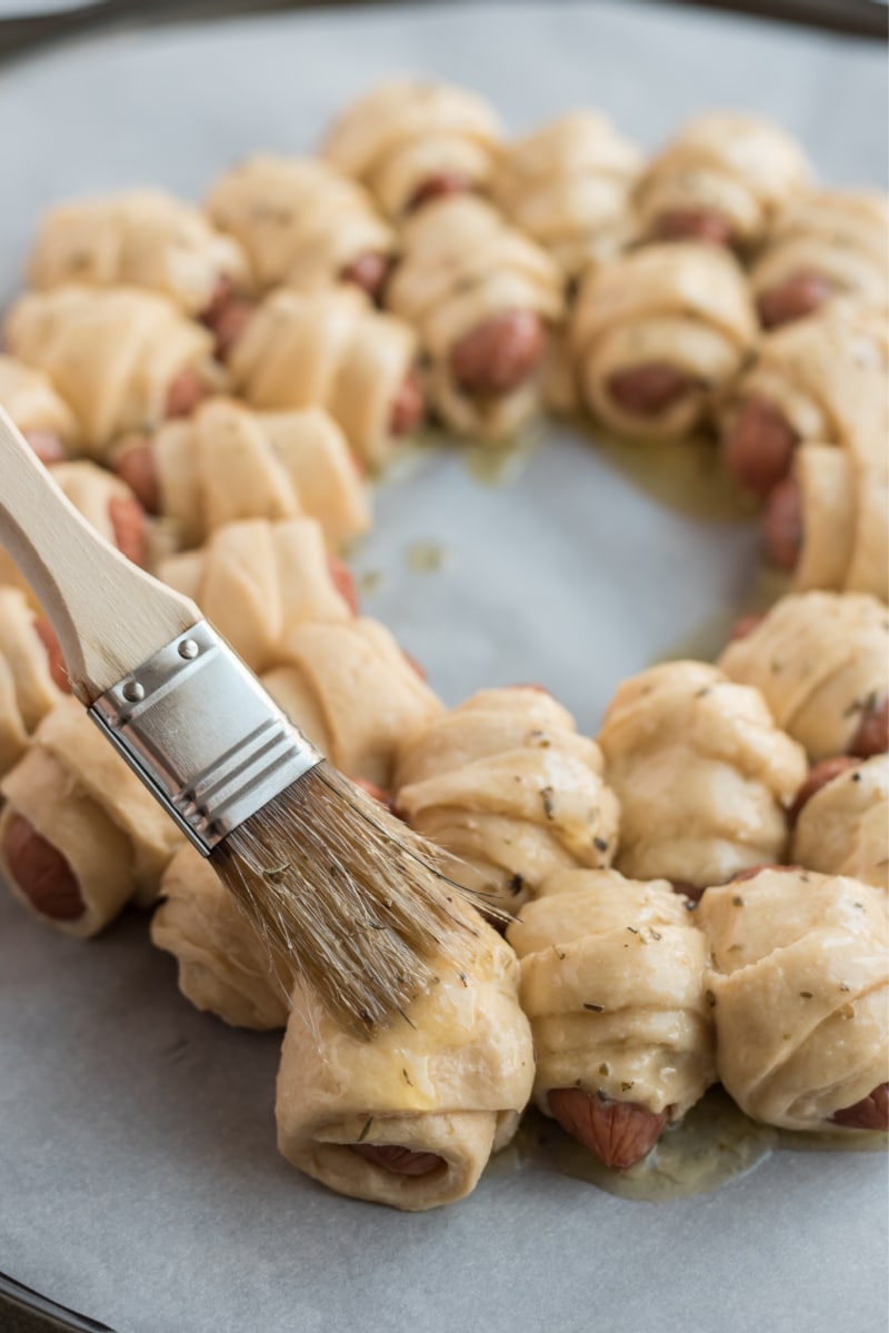 brushing herb butter on pigs in blanket