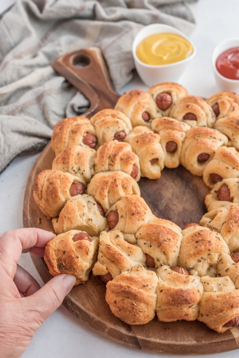 hand pulling pigs in blanket appetizer