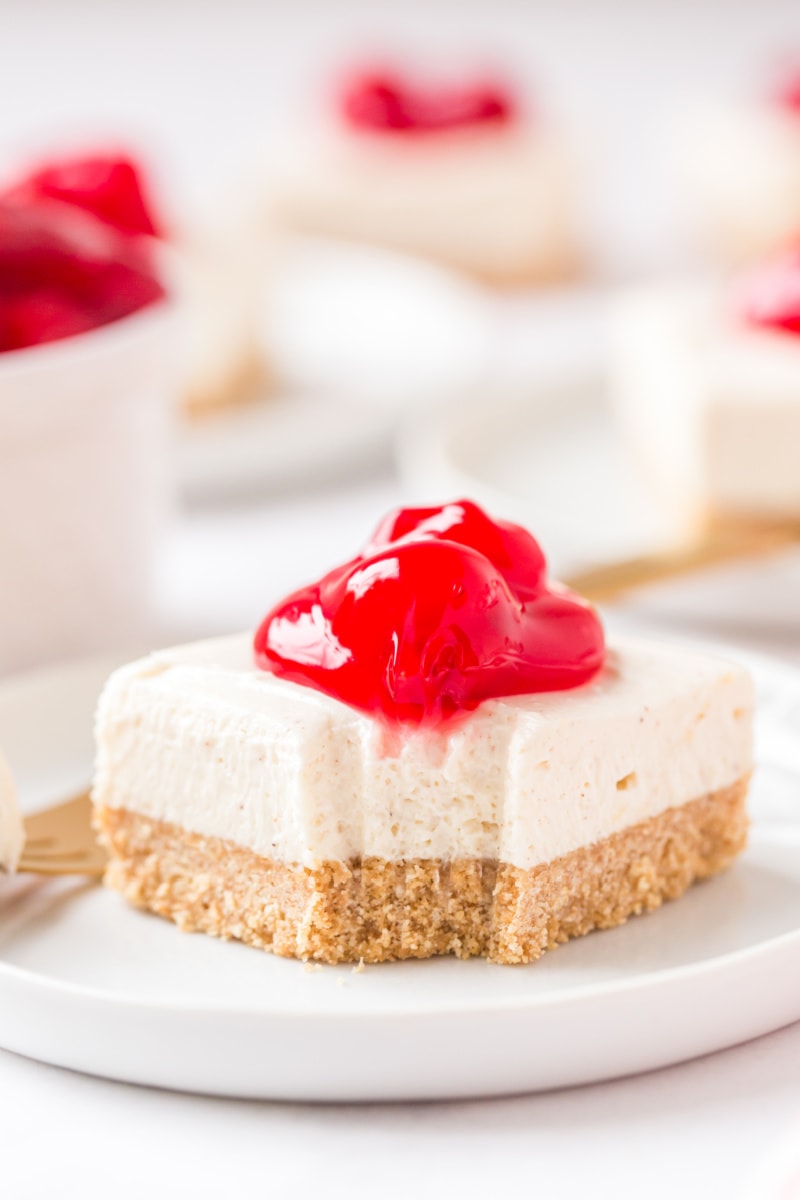 cherry cheesecake bar on white plate with bite out of it