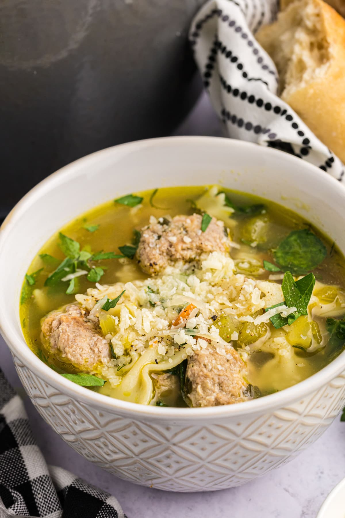 italian wedding soup topped with parmesan cheese in bowl