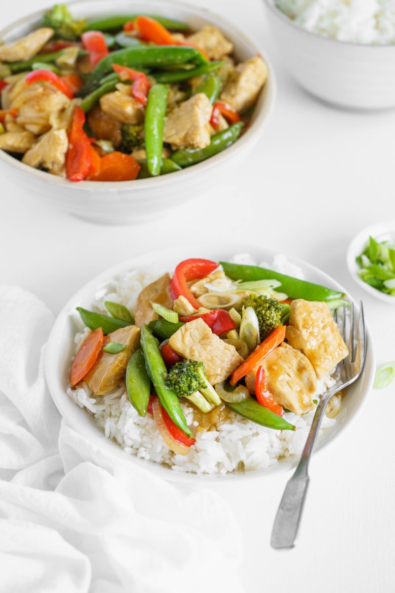 teriyaki chicken stir fry served over rice on white plates