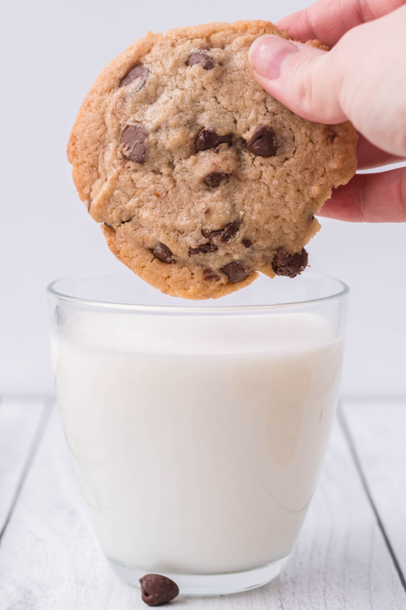 hand dunking cookie into a glass of milk