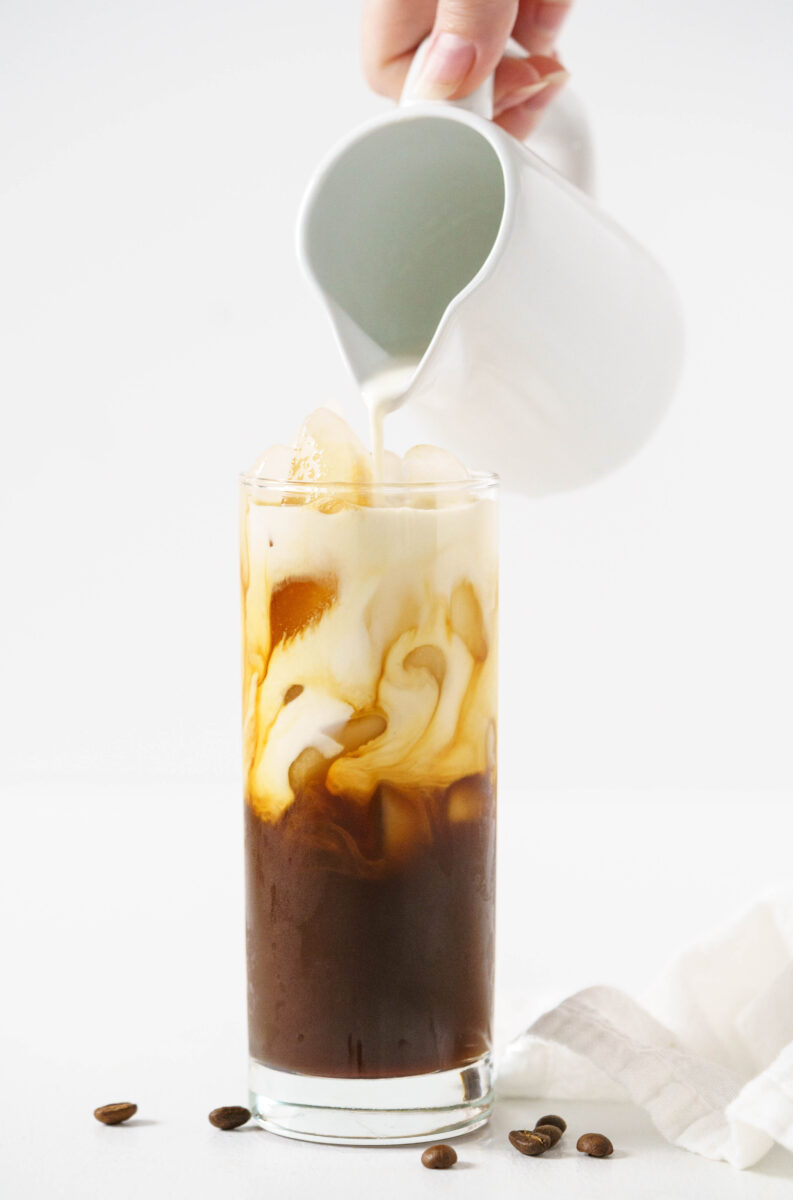 cream pouring into iced coffee